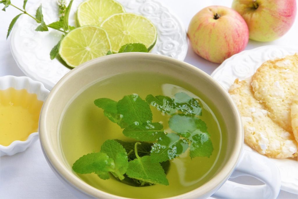 eine Schale grüner Tee mit ein paar Zitronen und Crackern