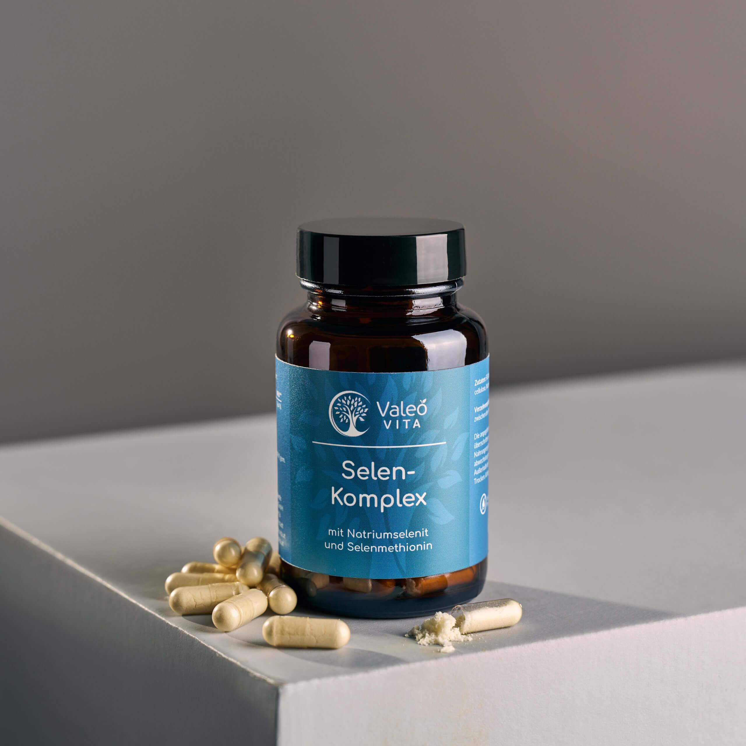 Valeo Vita Selen-Komplex Kapseln in Braunglasdose mit Kapseln und geöffnetem Kapselinhalt auf hellem Podest